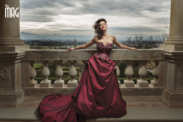 Lucia Rossi con vestito rosso elegante che posa a braccia distese nel terrazzo e panorama della alta valle tiberina