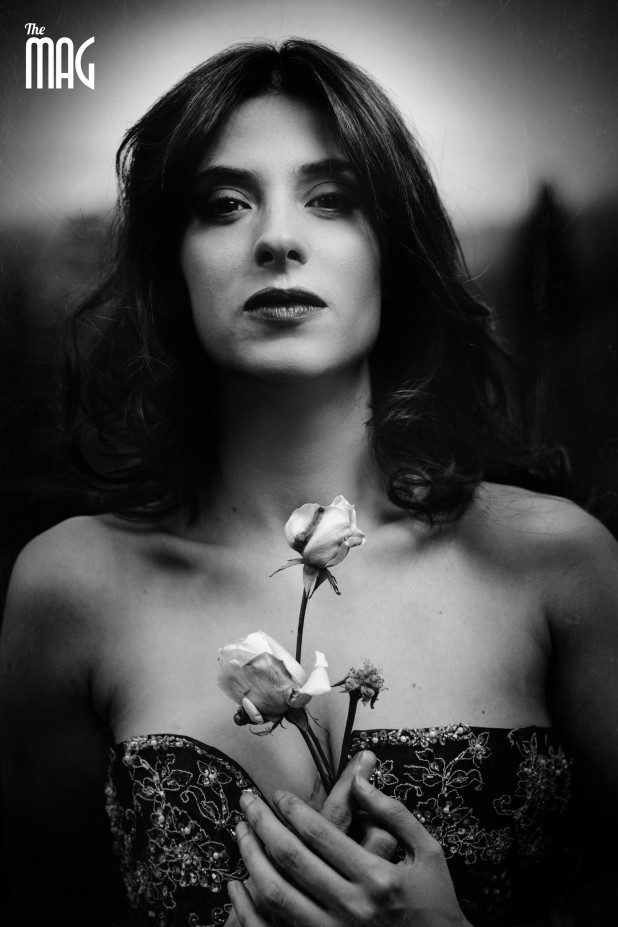Primo piano di Lucia Rossi in bianco e nero drammatico mentre tiene in mano una rosa