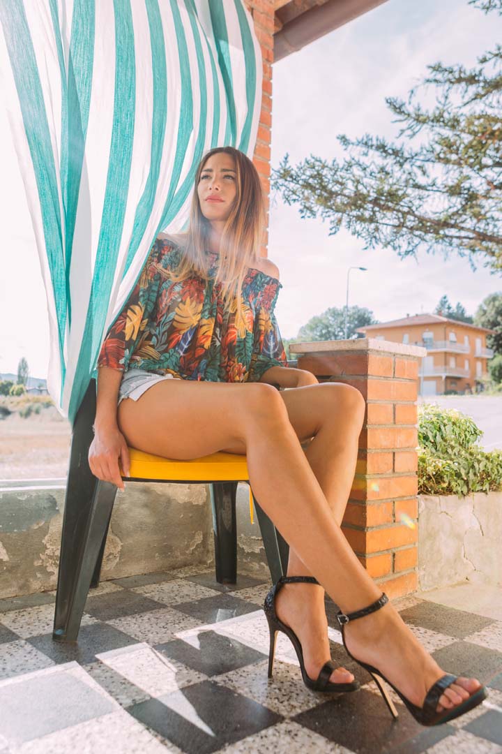 Monica Bartolucci mostra le gambe seduta in una terrazza