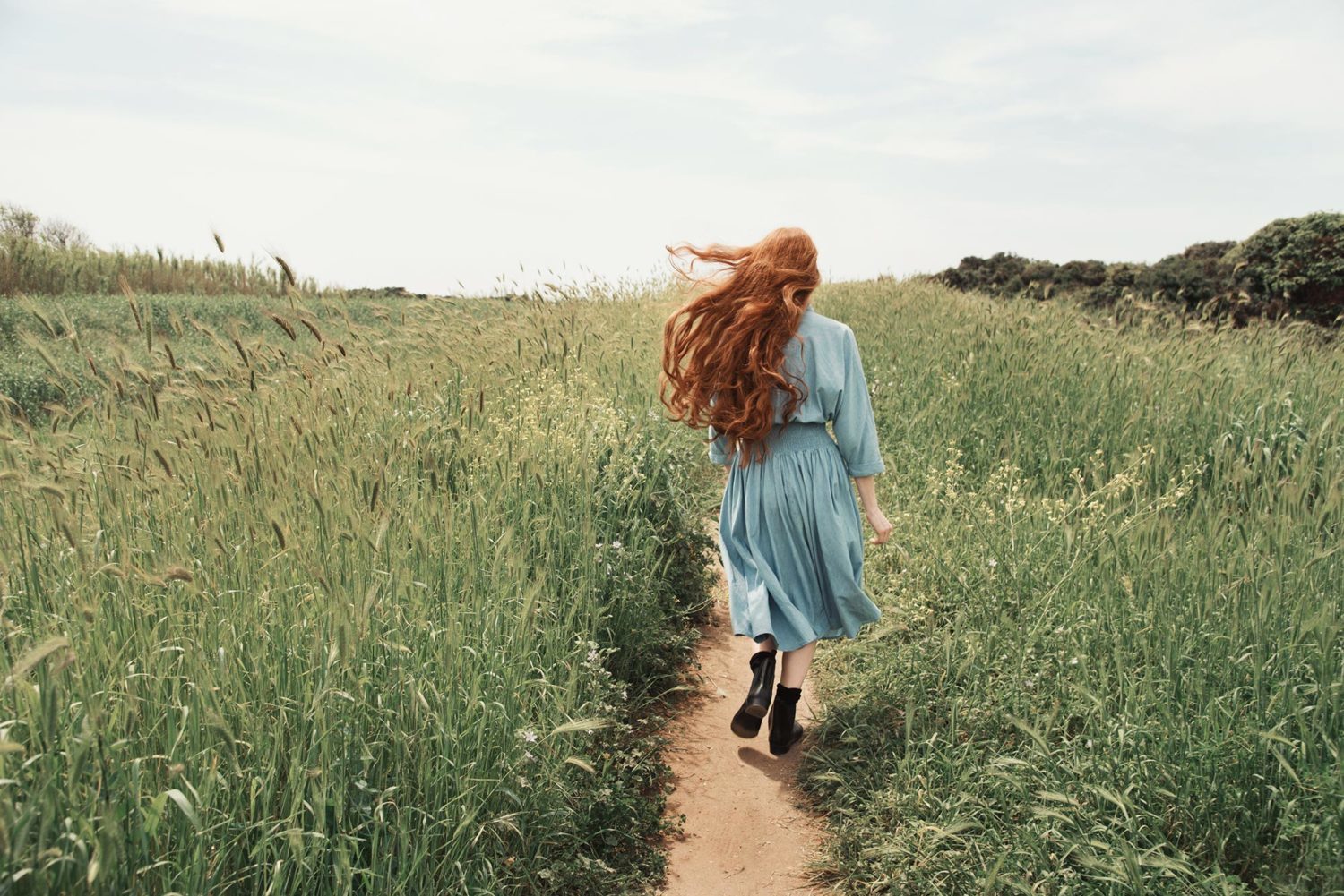 Giulia Beltrame cammina in un sentiero sterrato con i capelli rossi mossi dal vento